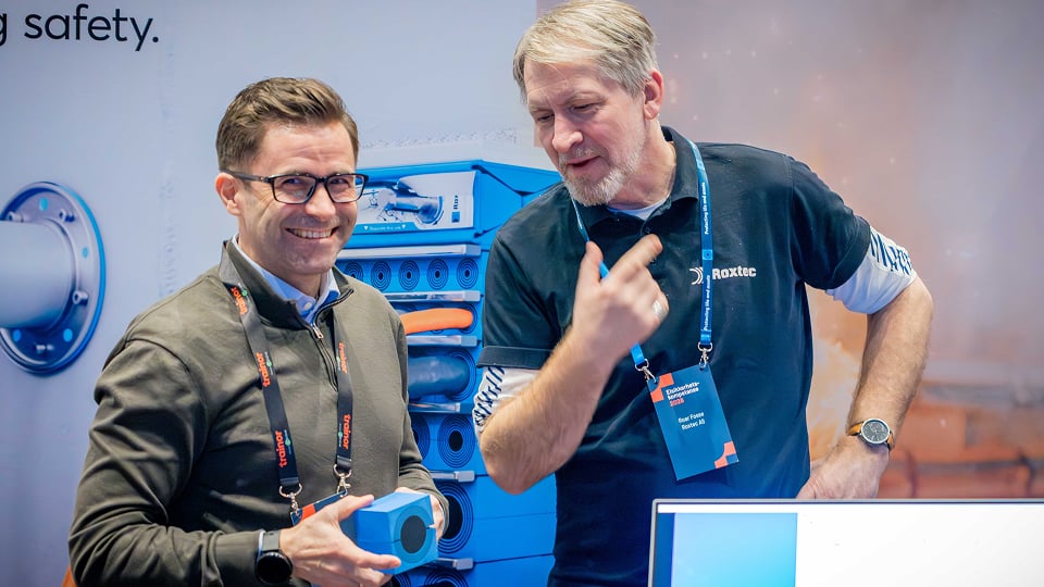 Two men at a trade show discussing a product at an exhibition stand.